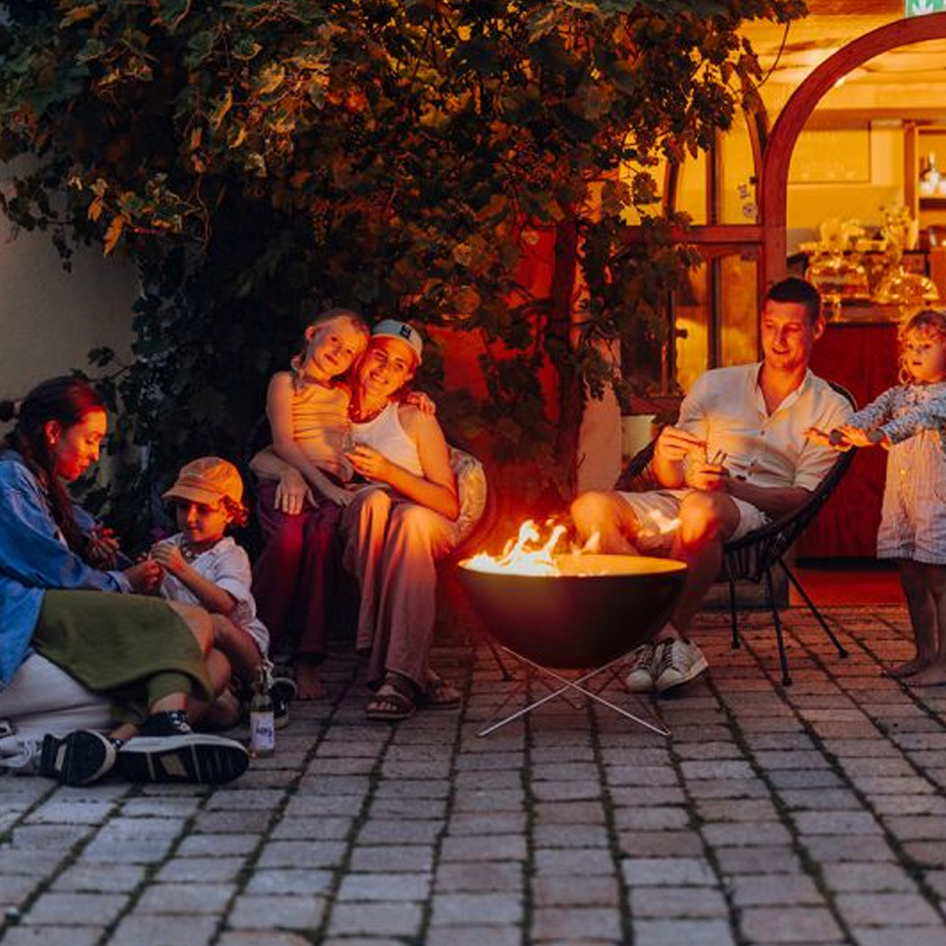 Fire Bowl 57 with star stand, outdoor gathering, Feuerstelle, Familienszene, Terrasse, Abendbeleuchtung